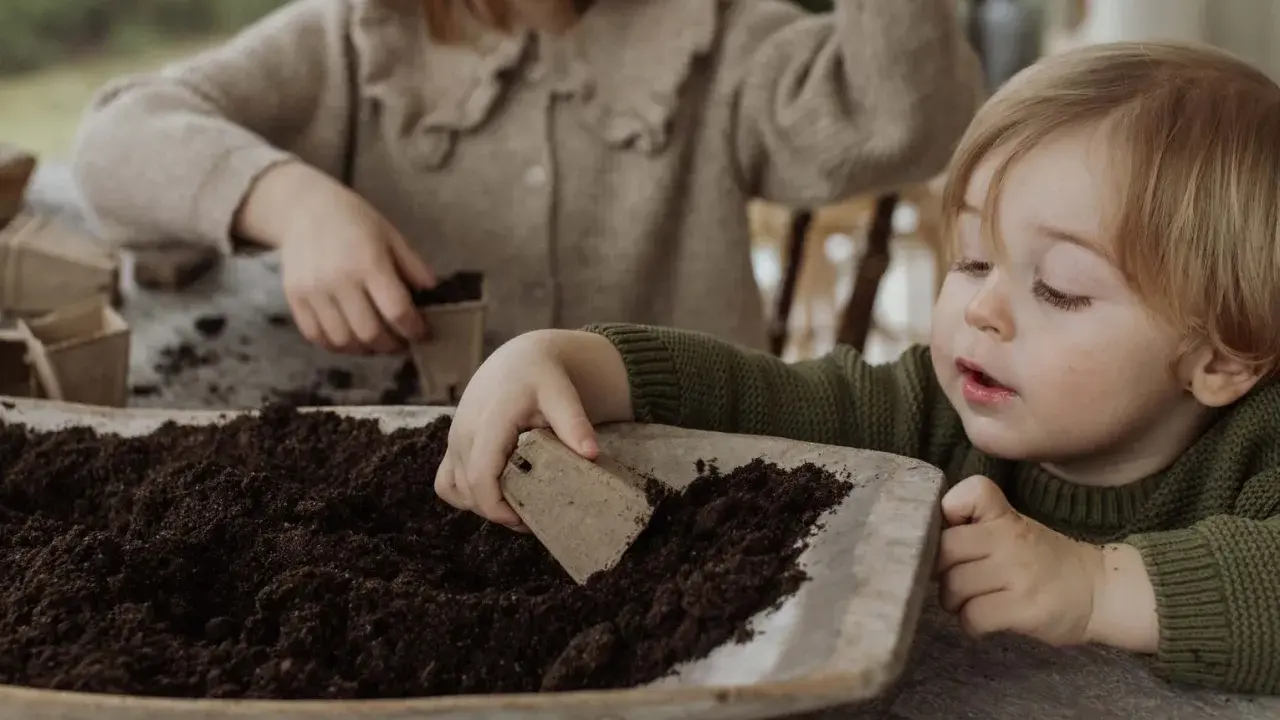 Two children planting seeds in soil.