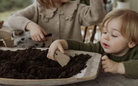 Two children planting seeds in soil.