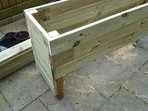 Nybyggd odlingslåda i tryckimpregnerat virke, redo att fyllas med jord och plantor.