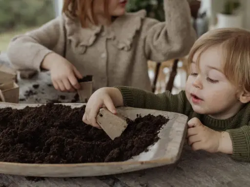 Two children planting seeds in soil.