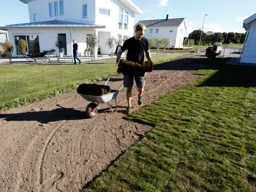 Man lägger ut färdig gräsmatta, rullar av grästorv för att skapa en ny moss lawn.